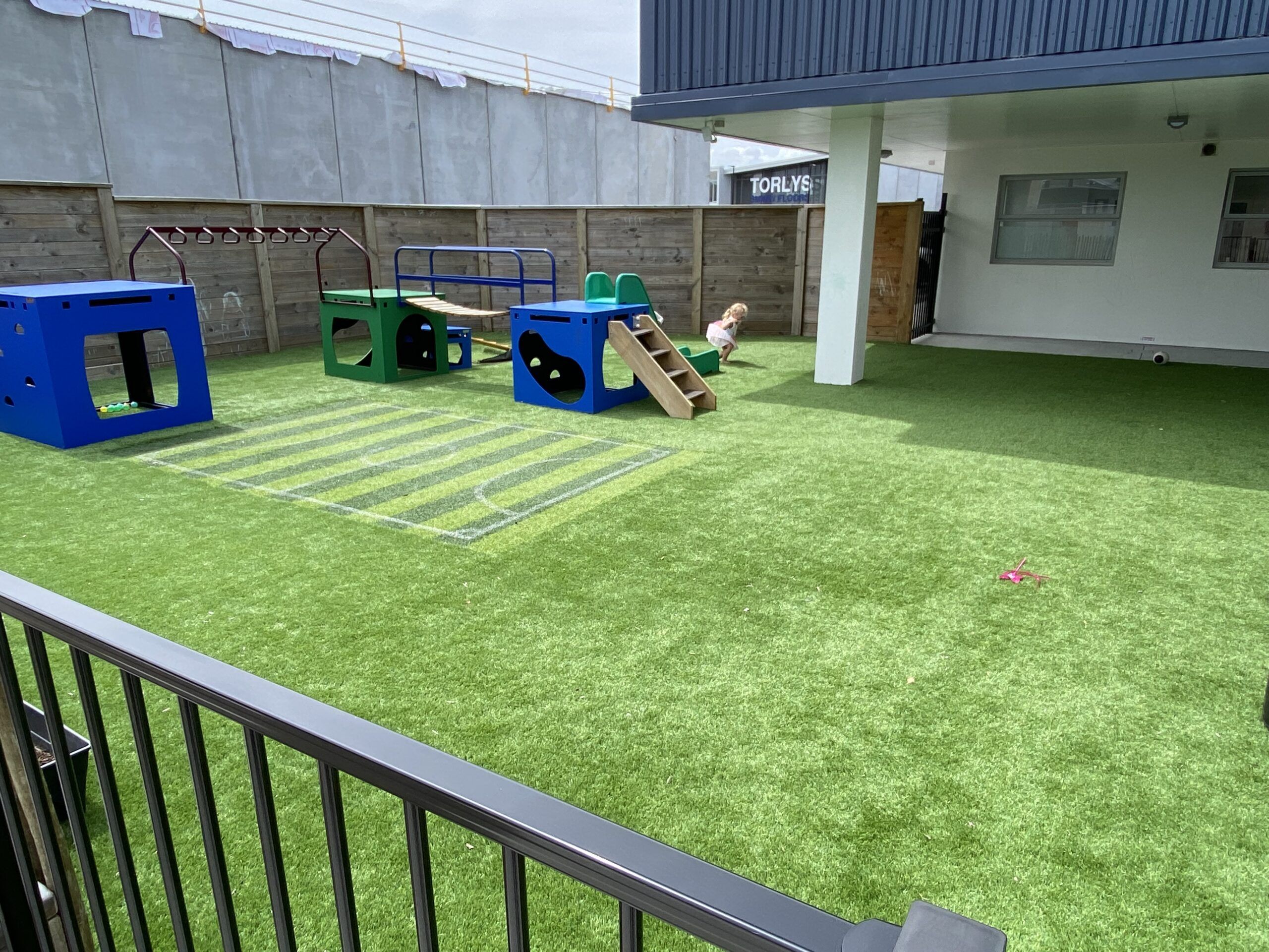 Nurture and Bloom | Outdoor playspace with playground equipment; boxes, slide, bridge and monkey bars