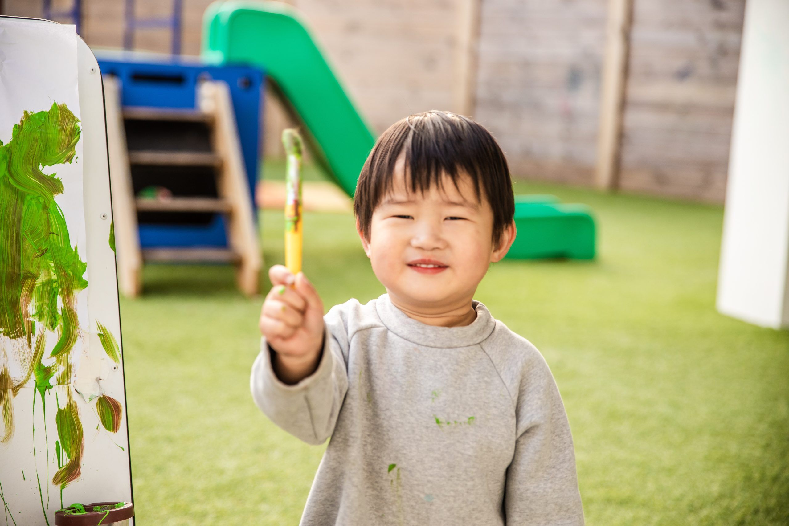 Nurture and Bloom | Child having fun painting outside in playground