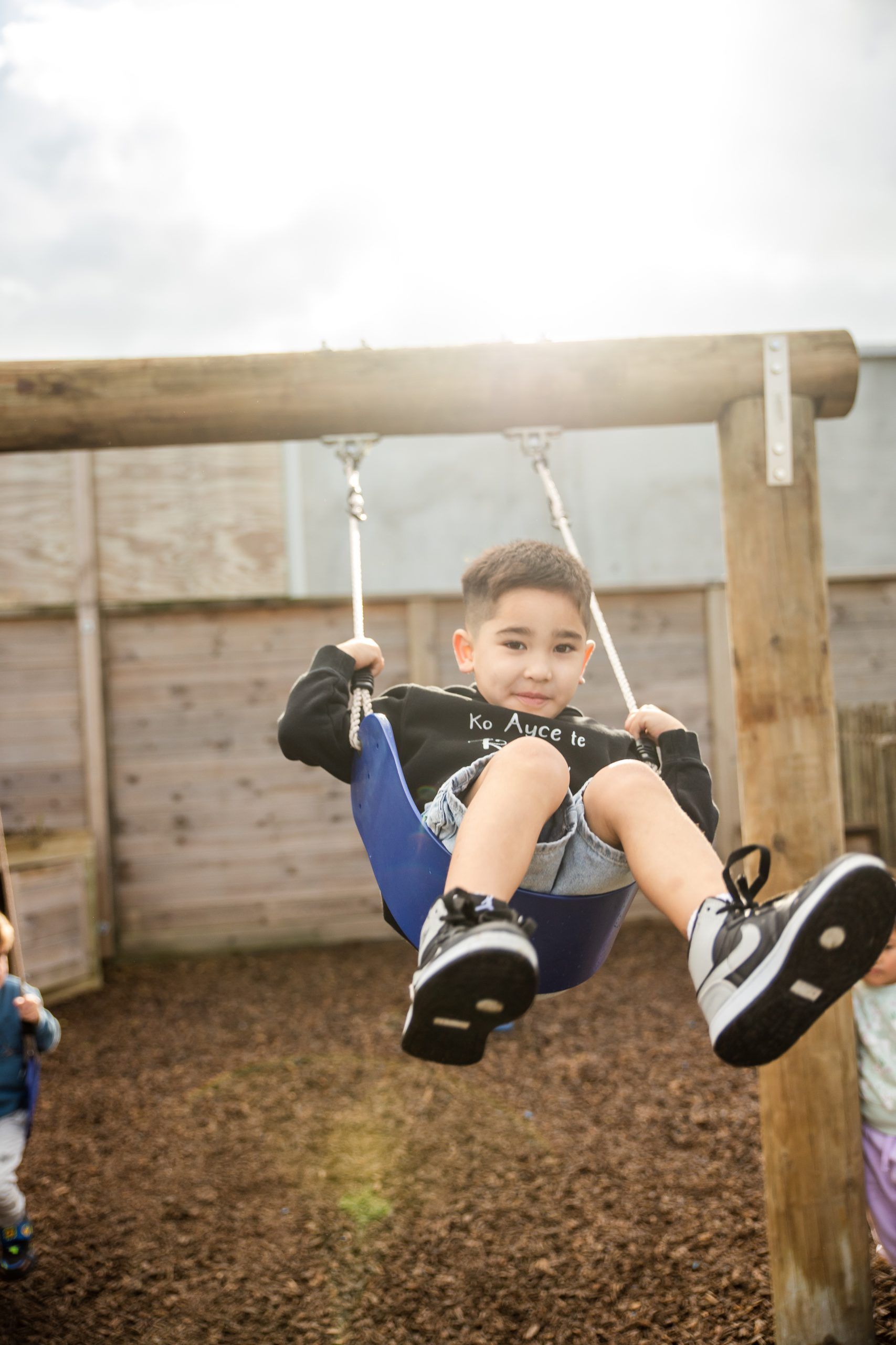 Nurture and Bloom | Child playing on wooden swing