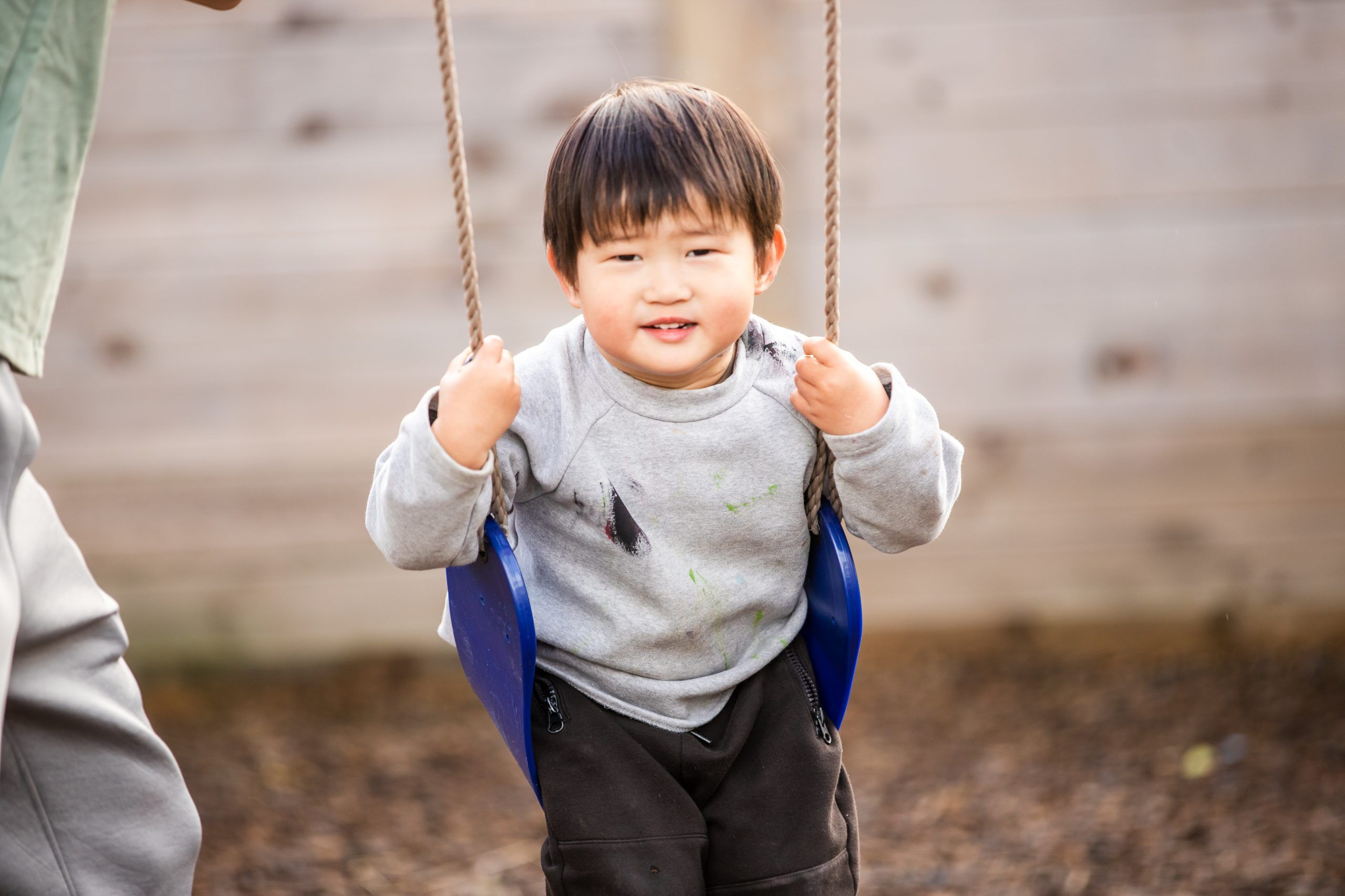 Nurture and Bloom | Child smiling on wooden swing