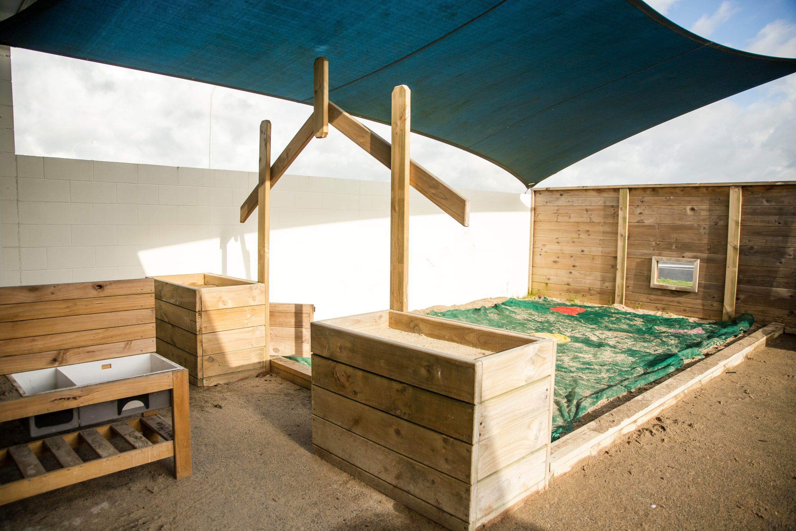 Nurture and Bloom | One of our playspaces with sandpit, shade sail and mud kitchen