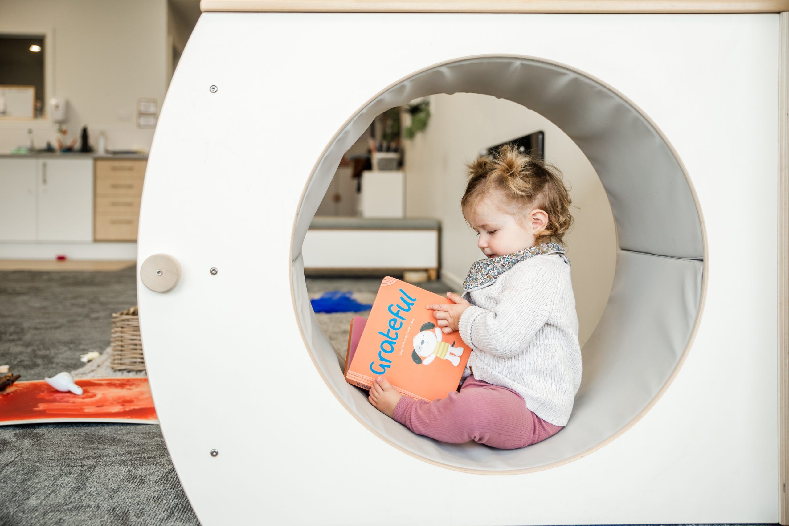 Nurture & Bloom | Child reading books in our play cubby hole