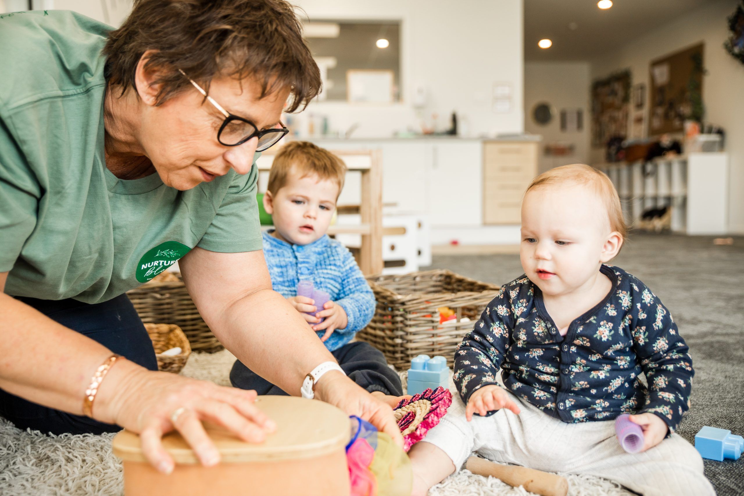 Nurture and Bloom | Teacher playing with babies with curistic play