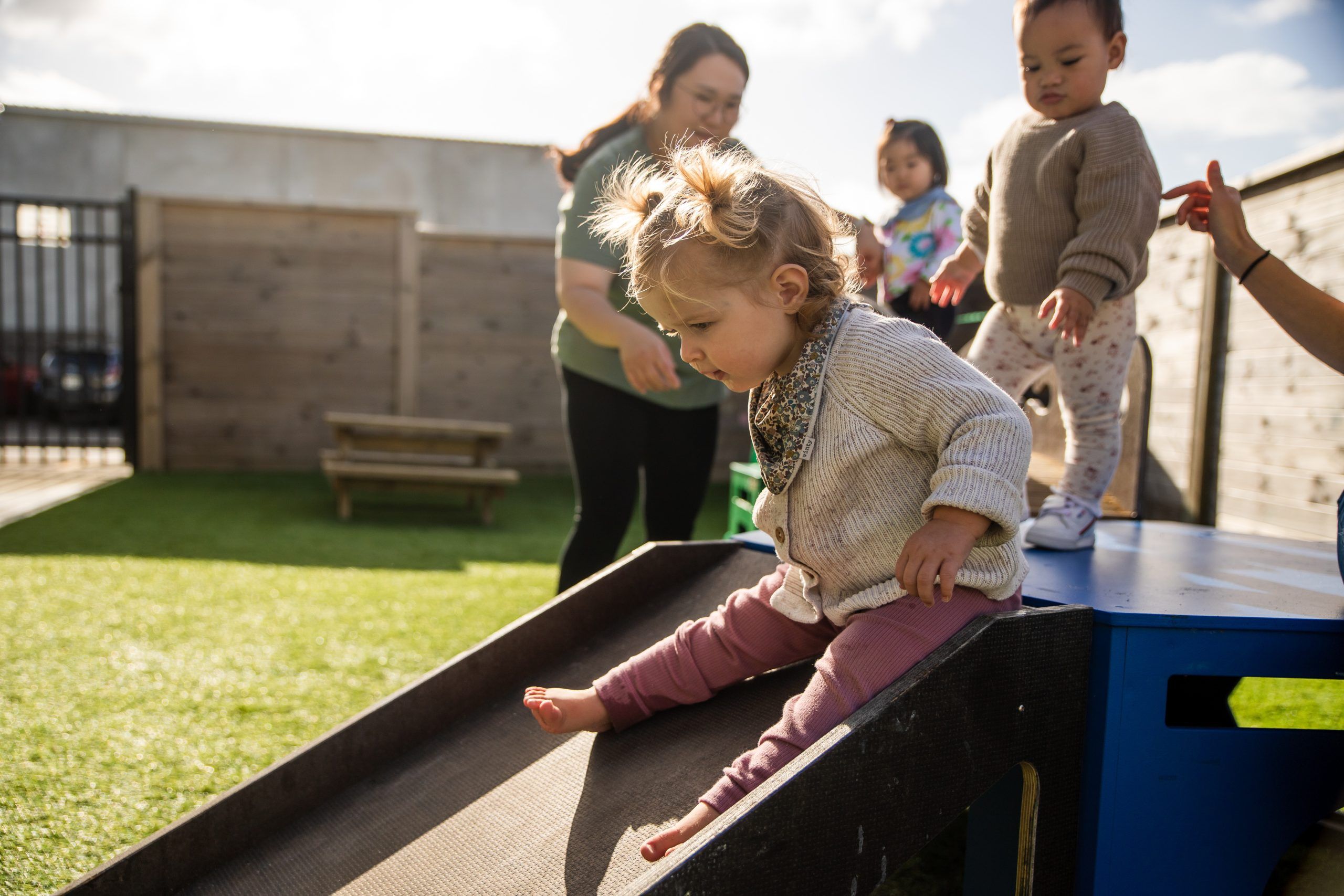 Nurture and Bloom | Child playing on slide in outdoor playground