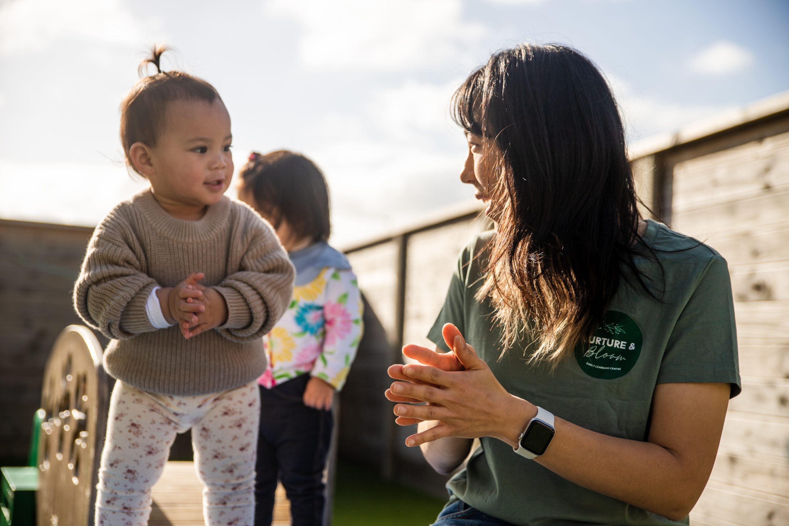 Nurture and Bloom | Teacher with kid on outside play equipment