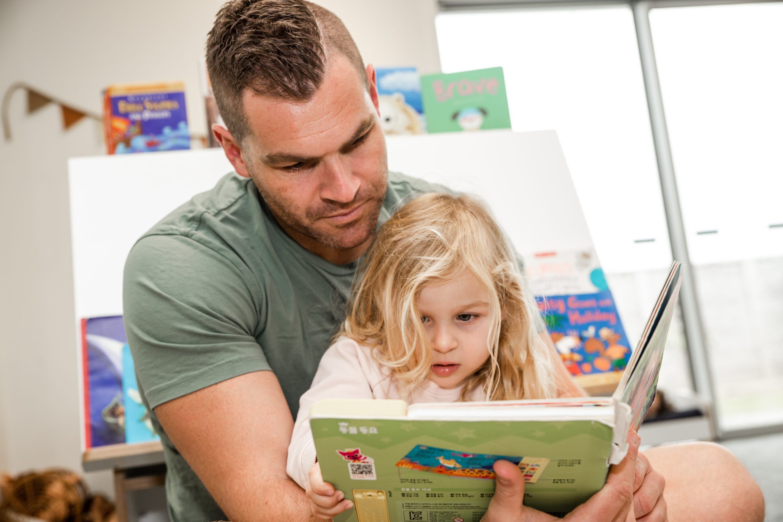 Nurture and Bloom | Teacher reading a book to child in mat time